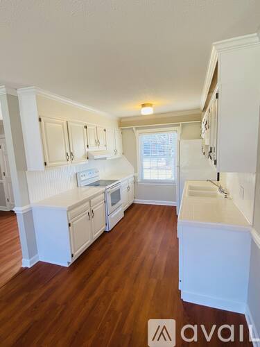 A kitchen with white cabinets and wooden floors.