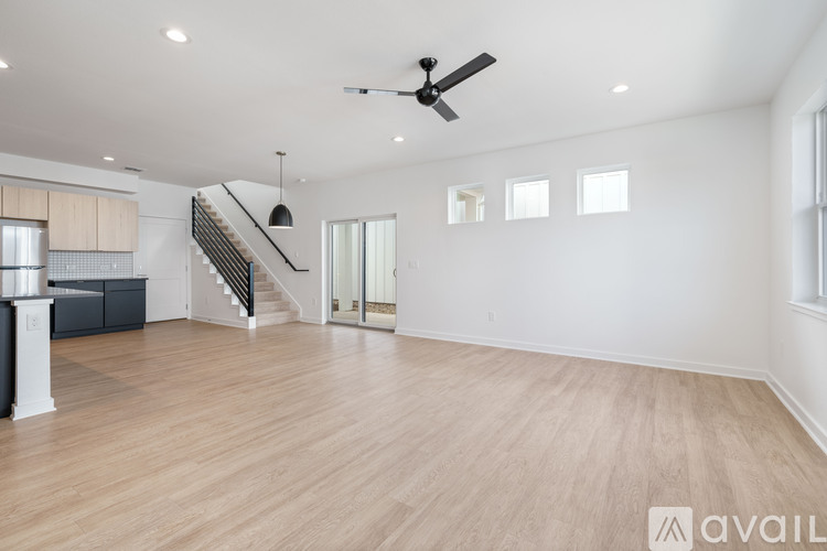 A spacious room with wooden flooring and a staircase.