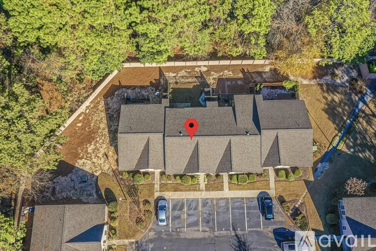 A bird's eye view of a parking lot with a building and a red marker on the roof.