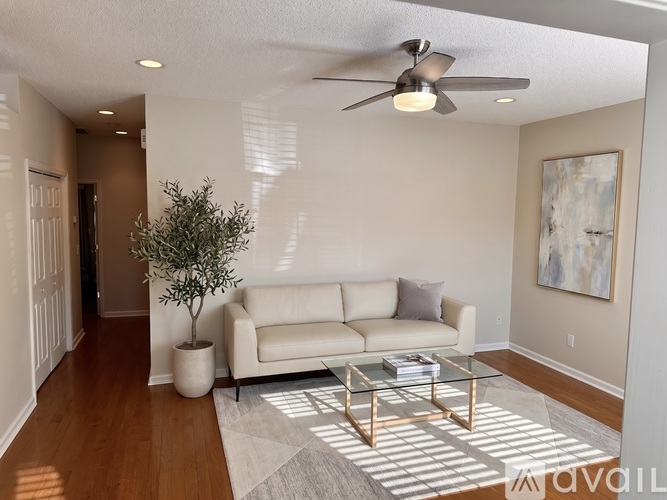 A living room with a white couch, a coffee table, and a ceiling fan.