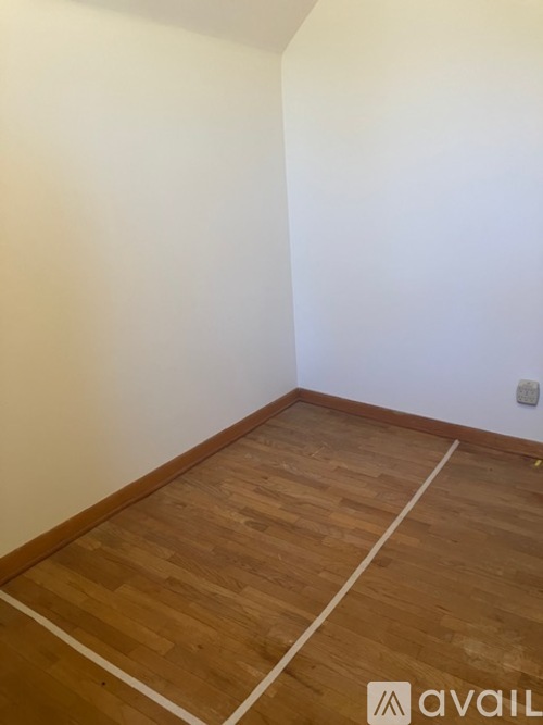 A room with wooden flooring and white walls.
