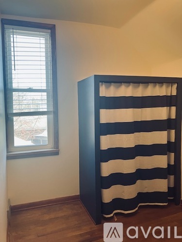 A tall black and white striped curtain hangs in a room with a window.