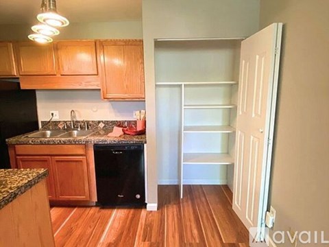 A kitchen with wooden cabinets and a black dishwasher.