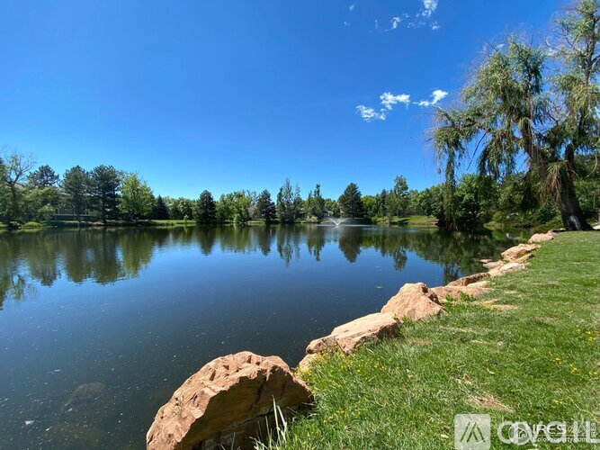 A serene lake surrounded by lush greenery and trees under a clear blue sky.