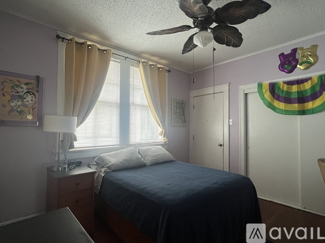 A bedroom with a bed, a ceiling fan, and a window with curtains.