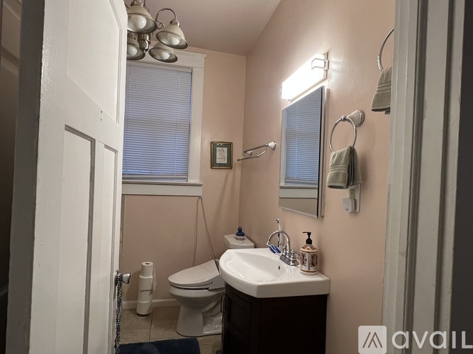 A bathroom with a toilet, sink, and mirror.