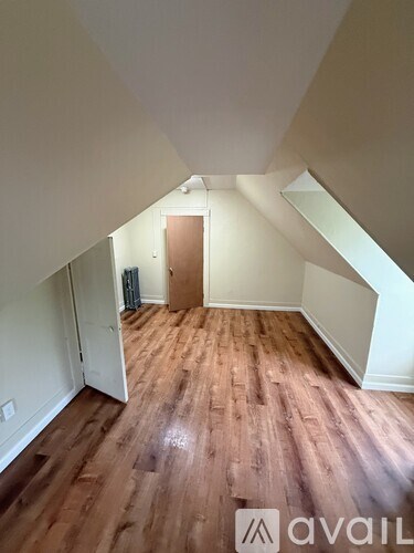 A room with wooden flooring and a door in the middle.