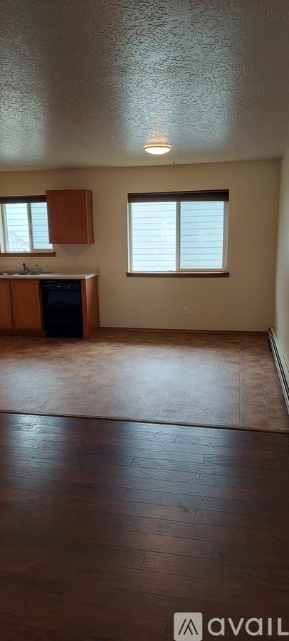 A kitchen with brown cabinets and a black trash can.