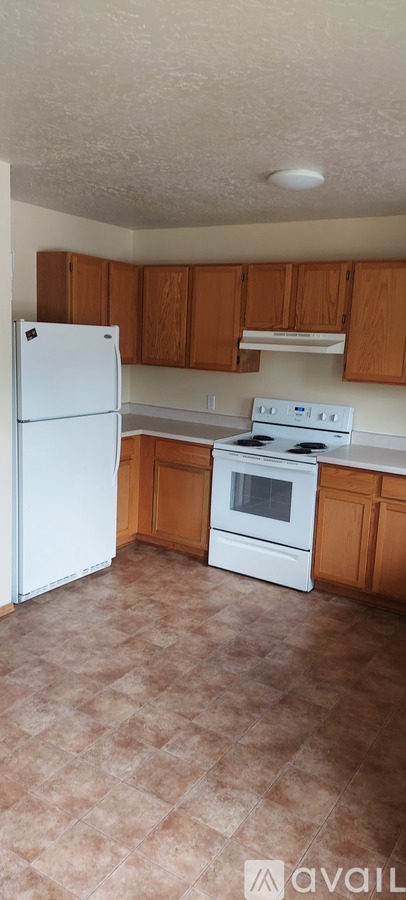 A kitchen with white appliances and wooden cabinets.
