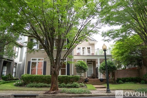 A house with a red door and a tree in front of it.