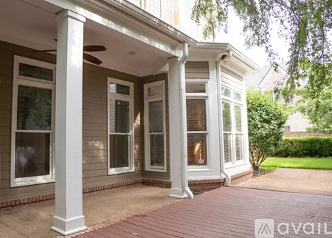 A porch with a ceiling fan and a covered walkway.