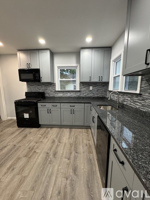 A kitchen with grey cabinets and black appliances.