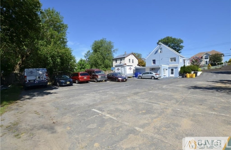 A parking lot with several cars and a white building in the background.