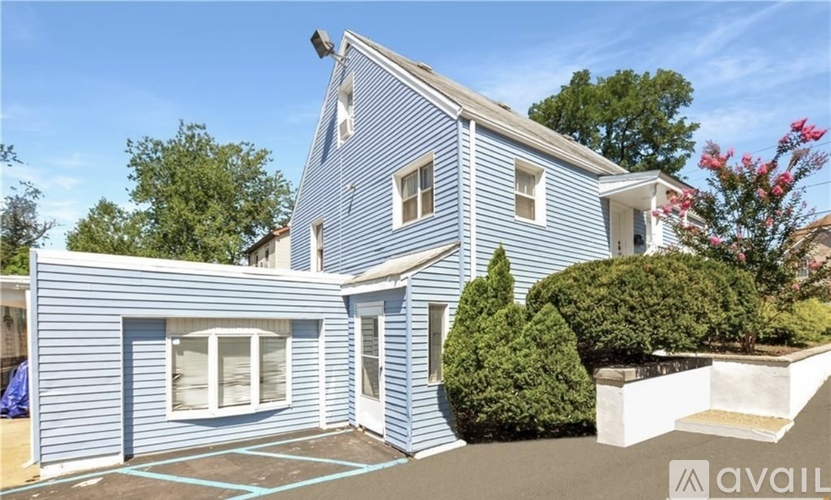 A blue house with a white roof and a small garden in front.