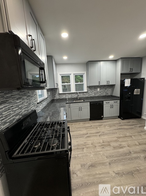 A kitchen with black appliances and a window.