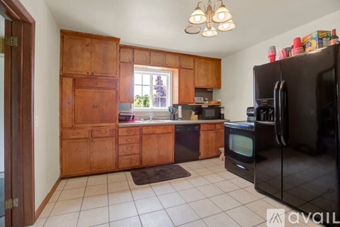 A kitchen with wooden cabinets and a black refrigerator.