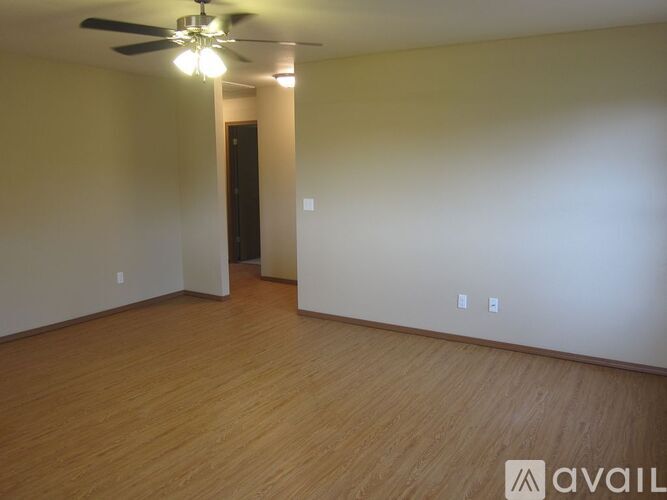 A room with a ceiling fan and wooden flooring.