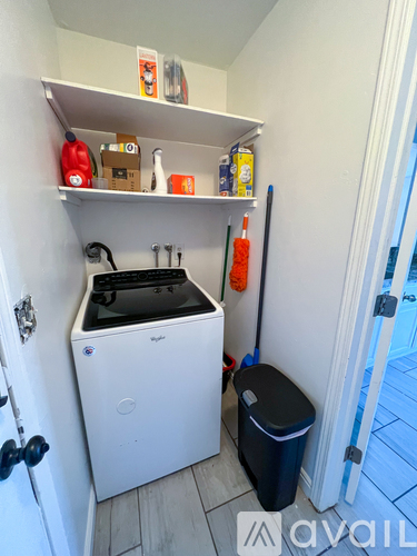 A small kitchen with a white dishwasher and a black trash bin.