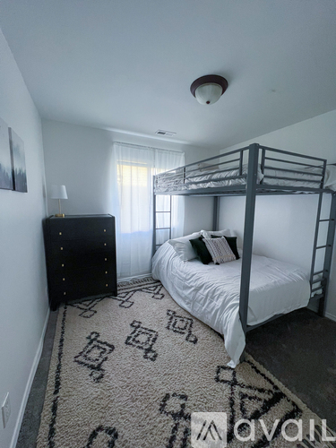 A bedroom with a bunk bed and a rug with a geometric pattern.