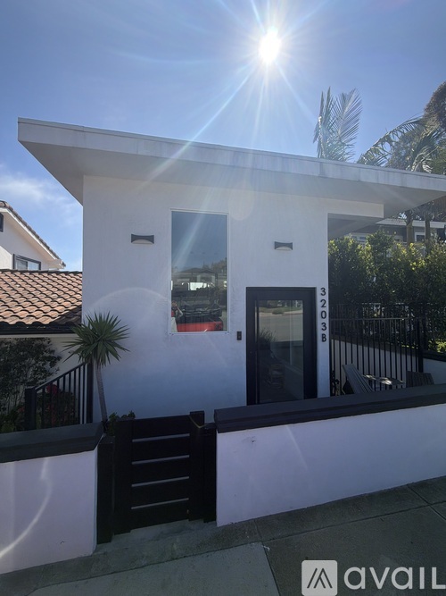 A modern house with a black gate and a sunny sky.