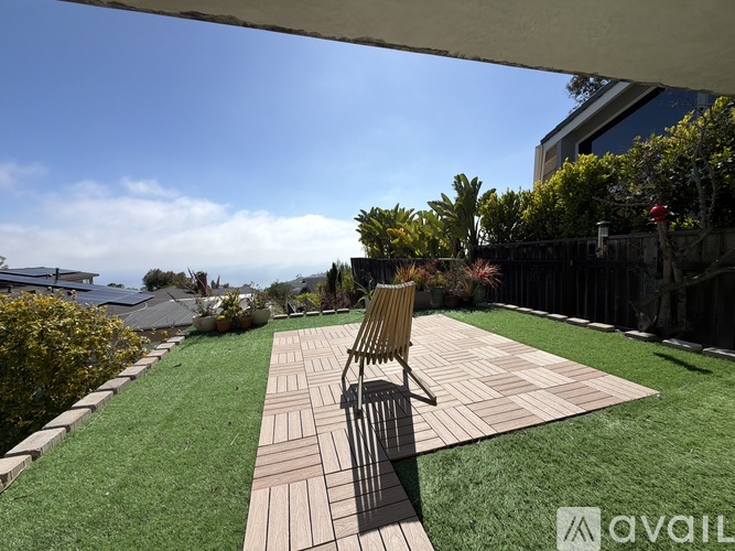 A wooden chair is placed on a wooden deck in a backyard.