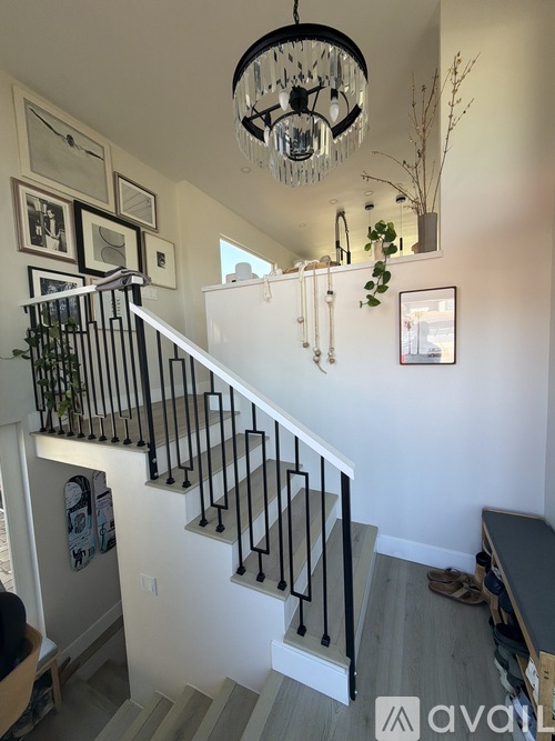 A staircase with a black railing and a chandelier hanging from the ceiling.