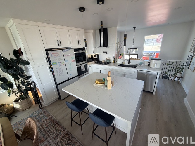 A kitchen with a table and chairs in the foreground and a fridge with magnets on it.