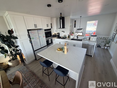A kitchen with a table and chairs in the foreground and a fridge with magnets on it.