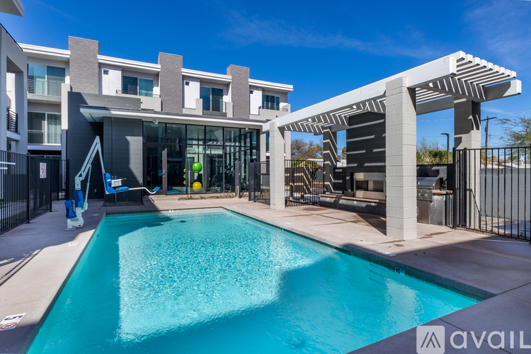 A swimming pool in front of a modern building with a poolside lounge area.