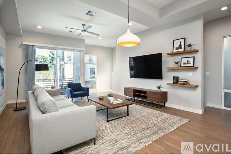 A living room with a white couch, a wooden coffee table, and a flat-screen TV mounted on the wall.