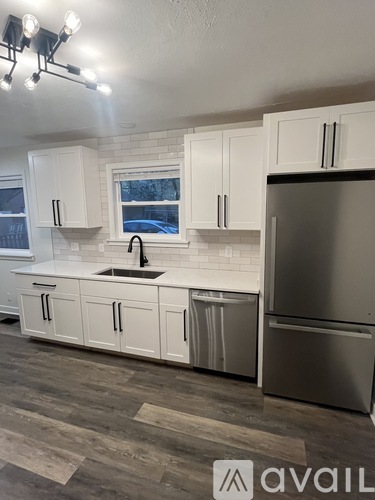A kitchen with white cabinets and a stainless steel refrigerator.
