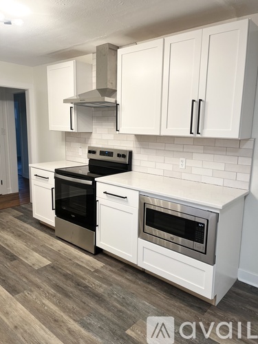 A kitchen with white cabinets and a wooden floor.