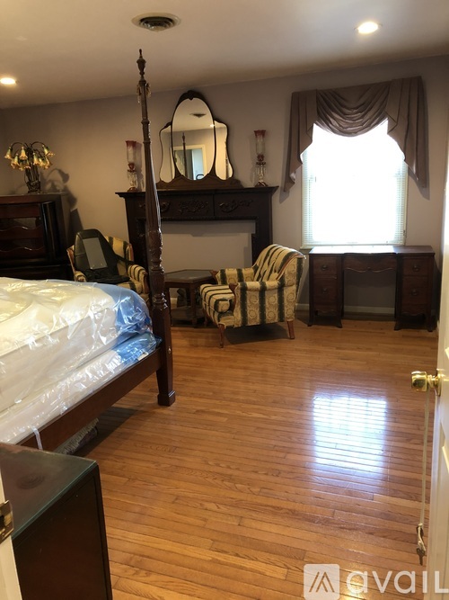 A bedroom with a four poster bed and a wooden floor.