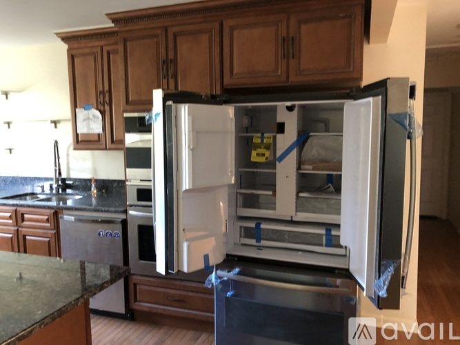 A kitchen with a refrigerator that is open and has a note attached to it.