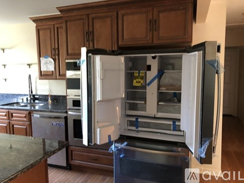 A kitchen with a refrigerator that is open and has a note attached to it.
