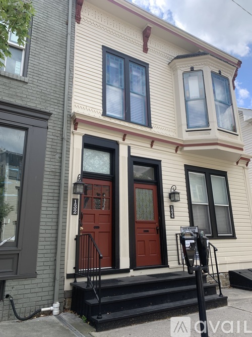 A two-story house with a red door and black railings.