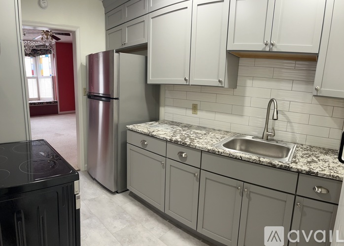 A kitchen with a black stove top oven and a silver refrigerator.