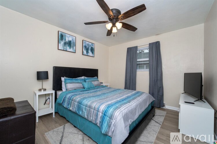 A bedroom with a bed, nightstand, and a ceiling fan.