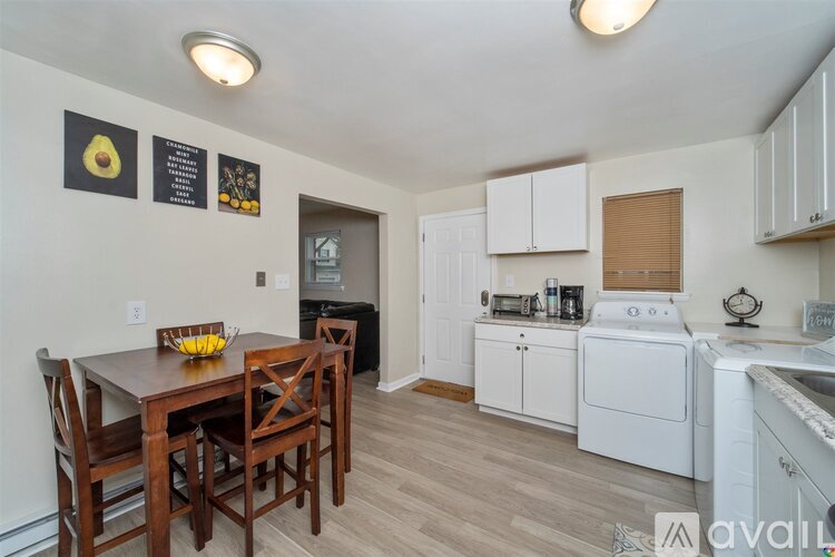 A kitchen with a table and chairs in the foreground and a washing machine in the background.