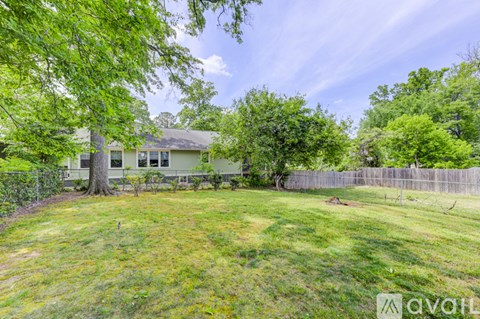 A house with a fence and trees in the yard.