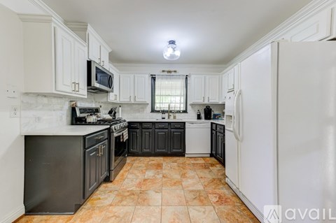 A kitchen with black cabinets and a white refrigerator.