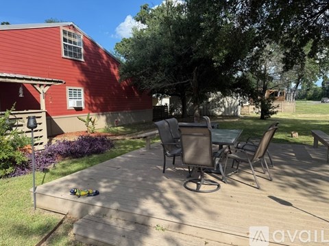 A patio with a table and chairs is in front of a red building.