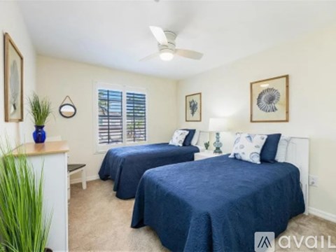A bedroom with two beds and a ceiling fan.