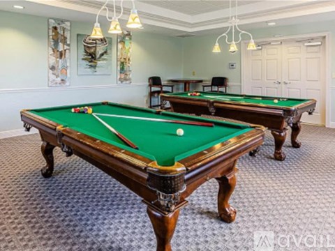 A room with two pool tables and a green felt one in the foreground.