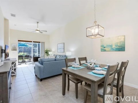 A dining room with a table set for four and a couch in the background.