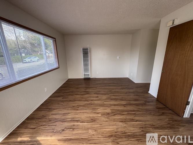 A room with wooden flooring and a window with blinds.