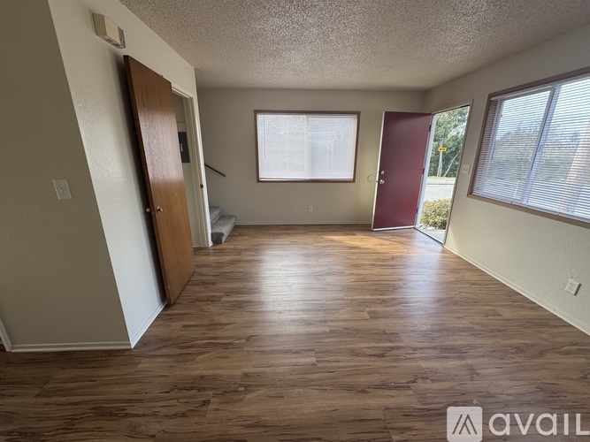 A room with wooden floors and two doors, one of which is red.