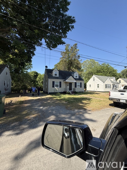 A truck is parked in front of a house with a view of the rearview mirror.
