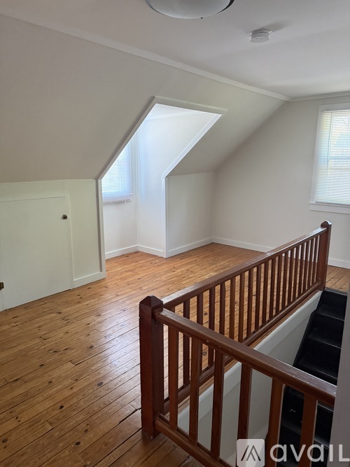 A room with wooden floors and a staircase leading to another room.