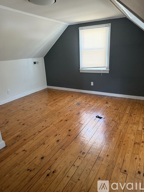 A room with wooden flooring and a window with blinds.